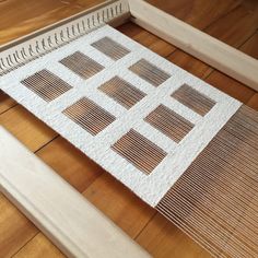 a close up of a weaving machine on a wooden floor with wood trimmings