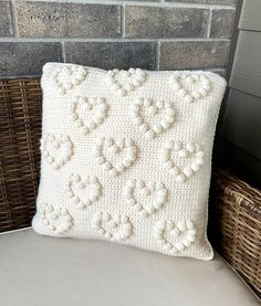 a white crocheted pillow sitting on top of a wicker chair next to a brick wall