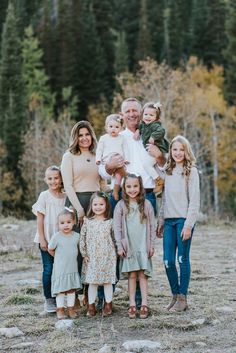 a family posing for a photo in front of some trees and rocks with their toddlers