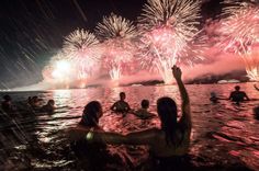 people are in the water watching fireworks go off