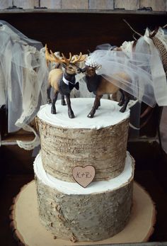 two deer figurines on top of a tree stump with a wedding dress and veil