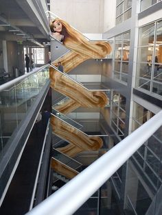 a woman with long hair standing on top of a stair case in an office building