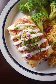 a white plate topped with food next to broccoli and rice covered in sauce