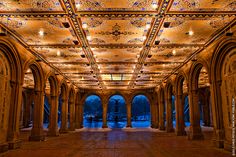 the inside of an ornate building with columns and arches, lit up by lights on either side