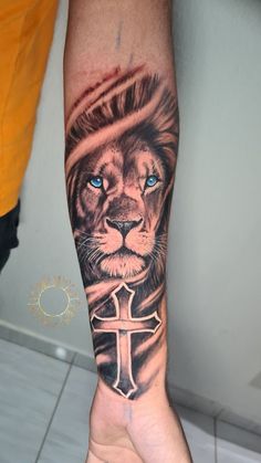 a man's arm with a lion and cross tattoo on it