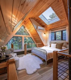 an attic bedroom with wooden walls and flooring is furnished with natural wood accents, including a white rug on the floor