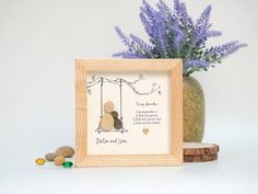 a wooden frame with a teddy bear sitting on a swing next to some rocks and flowers