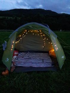 a tent is set up in the grass with lights on it