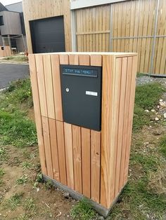 a wooden box sitting in the grass next to a building with a sign on it