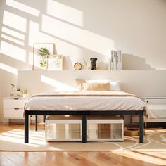 a bed sitting on top of a wooden floor next to a white dresser under a window