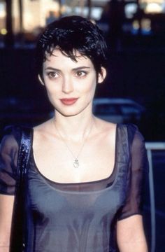 a close up of a person wearing a black shirt and holding a handbag in front of her face