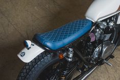 a white and blue motorcycle is parked in a garage with it's seat up