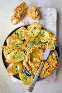 a plate filled with bread and dip next to garlic bread on a table top,