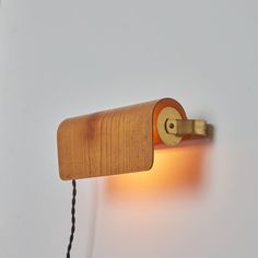 a wooden wall light with a cord attached to the back of it's arm