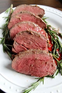 some meat is sitting on a white plate with green sprigs and ketchup