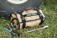 a tool bag sitting on the ground next to a tire with tools in front of it