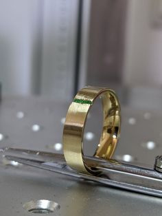 two gold wedding bands sitting on top of a piece of metal next to each other