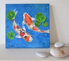 two koi fish swimming in a pond with lily pads and rocks on the side