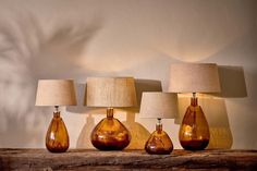 three brown glass lamps sitting on top of a wooden table next to a lamp shade