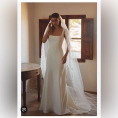 a woman in a wedding dress is talking on her cell phone while wearing a veil