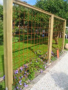 a garden with flowers growing on the side of it and a metal fence around it