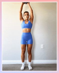 a woman in blue sports bra top and shorts holding up a black ball over her head