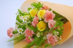 a bouquet of flowers sitting on top of a brown paper wrapped around a white surface