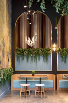 the interior of a restaurant with blue booths and plants hanging from the ceiling above them