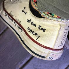 someone's shoes with writing on them and a hat hanging off the side of one shoe