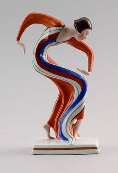 a figurine that is standing on a white base with red, blue and green stripes