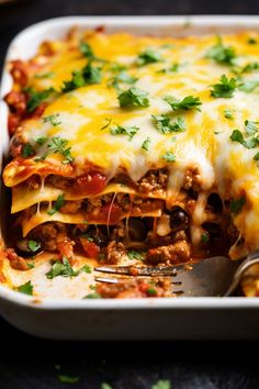 a lasagna casserole with meat, cheese and vegetables in a white dish