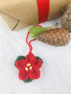 a crocheted ornament with a pine cone next to it on a white surface