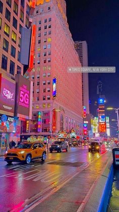 a city street filled with lots of traffic and tall buildings in the background at night