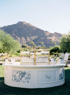 an outdoor ceremony setup with white chairs and flowers on the table in front of mountains