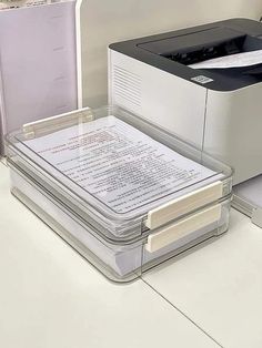 a printer sitting on top of a desk next to a box with papers in it