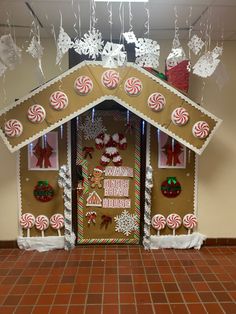 a gingerbread house decorated for christmas with candy canes and snowflakes hanging from the roof