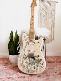 an electric guitar sitting on top of a rug next to a potted plant