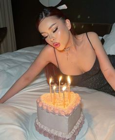 a woman sitting in front of a cake with lit candles