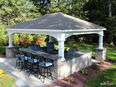 an outdoor bar with stools and tables under a gazebo in the middle of a park