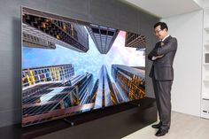 a man standing in front of a flat screen tv with the city skyline on it