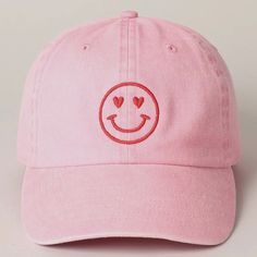 a pink hat with a smiley face embroidered on it