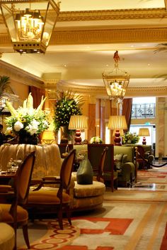 a hotel lobby filled with lots of furniture and flowers in vases on the tables