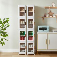 a tall white cabinet with wine glasses on it next to a potted plant and microwave