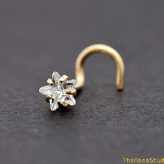 a gold nose ring with a clear crystal star on it's end, sitting on a black surface