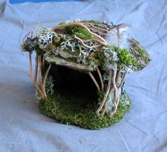 a moss covered bird house on top of a white sheeted surface with blue background