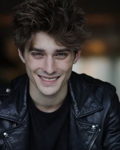 a smiling young man wearing a black leather jacket