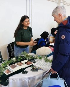 an older man standing next to a woman at a table with flowers and pictures on it