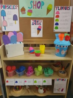 a display case with ice cream, cupcakes and other items on the shelves