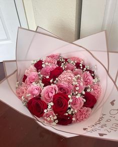 a bouquet of pink and red roses in a box