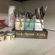 there are many mason jars with forks in them on the shelf next to each other